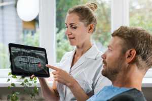 dentist showing and explaining dental x-ray picture with impacted wisdom tooth to her patient